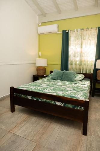 a bedroom with a bed with a green comforter at Exotic Villa avec Piscine in Le Vauclin