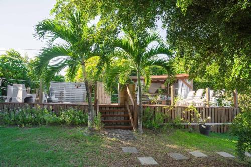 a house with two palm trees and a fence at Exotic Villa avec Piscine in Le Vauclin
