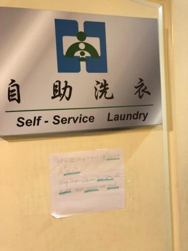 a sign for a self service laundry hanging on a wall at Large family room near Metro Taipei station for comfort and convenience, where 5 can relax and create unforgettable moments in Taipei