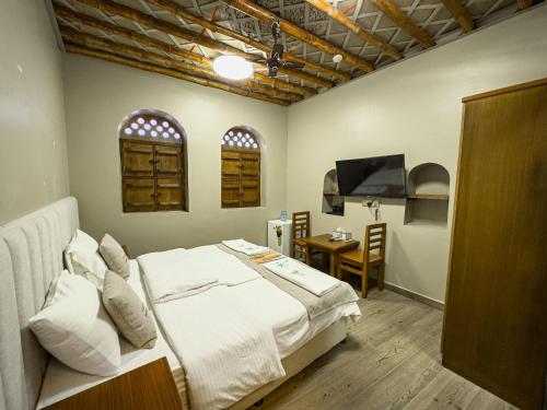 a bedroom with a bed and a table and a television at IHYAA Inn - نزل إحياء in Nizwa