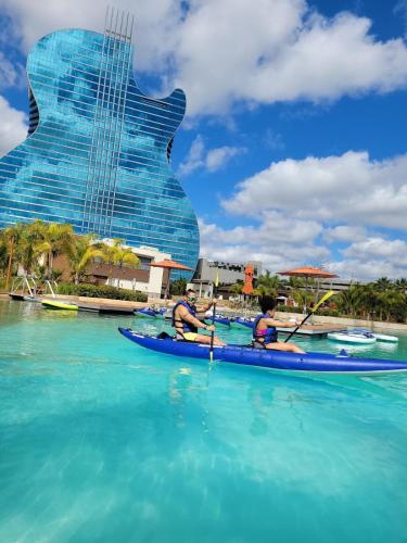 two people kayaking in the water in front of a guitar shaped building at AMIRI Hollywood 5 mins from Hard Rock Stadium & The Guitar in Hollywood