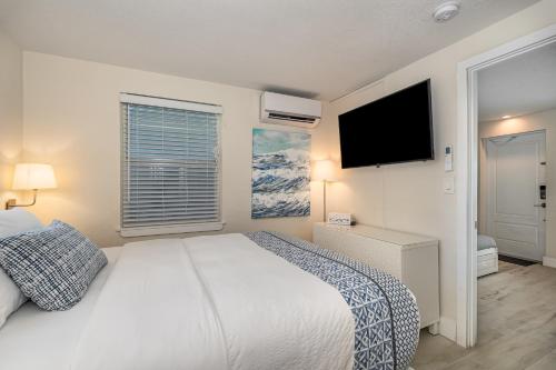 a bedroom with a white bed and a flat screen tv at Wonderful Place Wprivate Patio Next To The Beach in Cocoa Beach