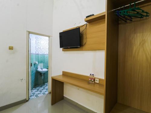 a room with a tv on the wall and a bathroom at Prayogo Style Inn Prawirotaman in Yogyakarta
