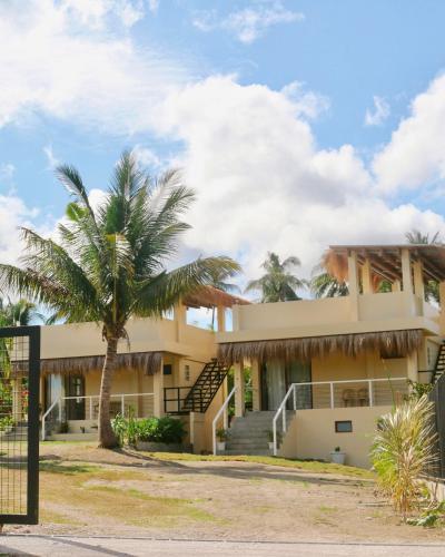 a building with a palm tree in front of it at Casa De Amor Lambug in Badian