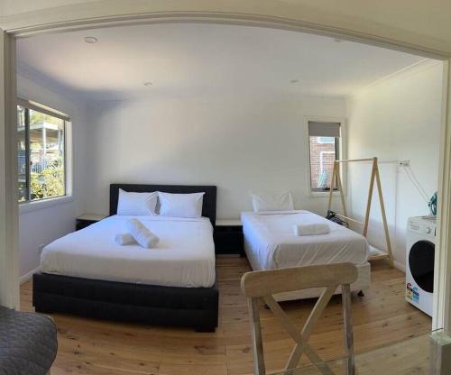 a bedroom with two beds and a chair in it at Studio house Unit in Dundas Valley in Sydney