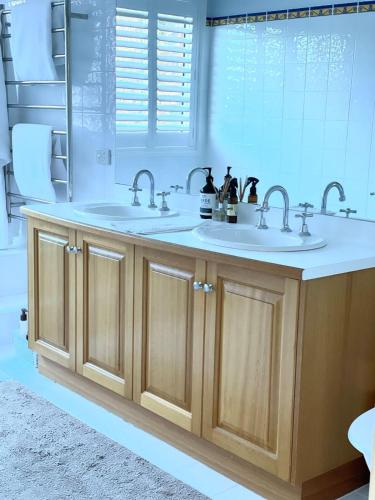 a bathroom with two sinks and a mirror at Beautiful Home Away From Home in Bowral in Bowral