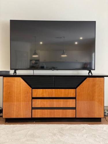 a large television on top of a wooden entertainment center at Beautiful Home Away From Home in Bowral in Bowral