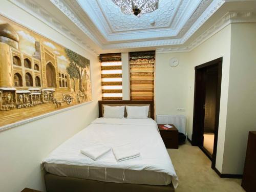 ein Schlafzimmer mit einem Bett und einem Gemälde an der Wand in der Unterkunft Orbita Villa boutique in Buxoro