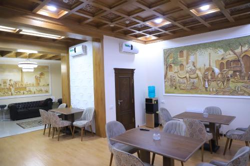 ein Zimmer mit Tischen und Stühlen und einem Wandgemälde in der Unterkunft Orbita Villa boutique in Buxoro