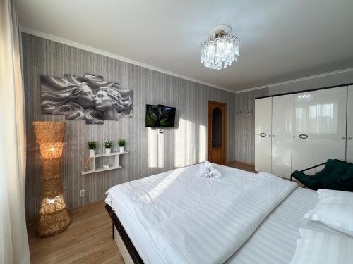 a bedroom with a large white bed and a chandelier at Апартаменты стандарт in Pavlodar