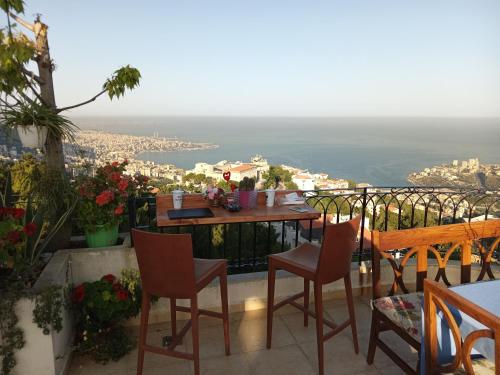 a table and chairs on a balcony with a view at Arcadia Guesthouses - Ghazir, Lebanon in Ed Dkârîne