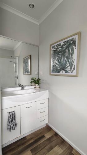 a white bathroom with a sink and a mirror at Hamilton East Haven in Hamilton