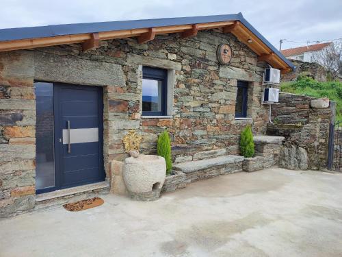 a stone house with a blue garage door and a stone wall at Castas D'ouro Guest House in Casal de Loivos