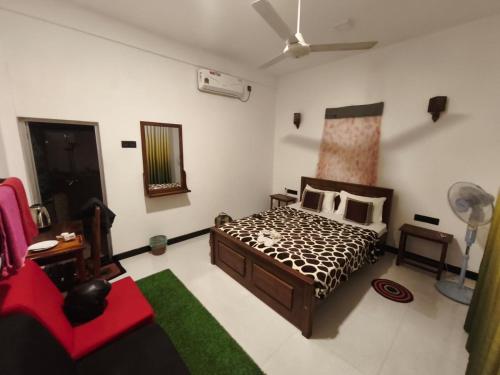 a bedroom with a bed and a red couch at Nature World Udawalawe in Udawalawe