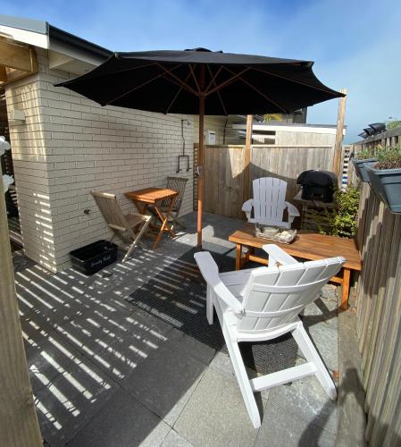 a patio with a table and chairs and an umbrella at Beautiful Bream Bay Studio - Ruakaka in Ruakaka