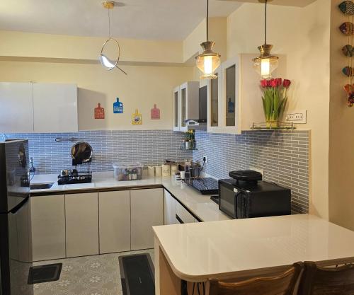 a kitchen with white cabinets and a counter with roses at Beachwalk- A Luxury 1BHK Apartment Nearby Candolim Beach Goa in Goa