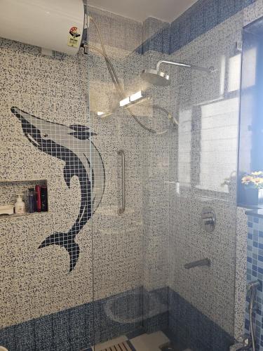 a bathroom with a shower with a dolphin on the wall at Beachwalk- A Luxury 1BHK Apartment Nearby Candolim Beach Goa in Goa