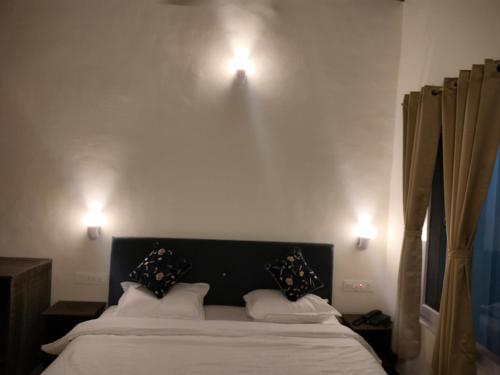 a bedroom with a bed with two lights on the wall at Misty Mount By Himalayan Tree Hotels in Bhowāli