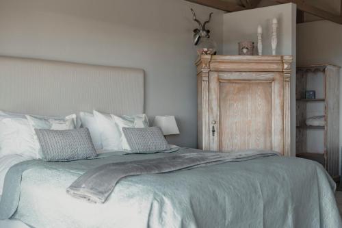 a bedroom with a bed and a wooden cabinet at The Ocean Bay Luxury Guesthouse in Jeffreys Bay