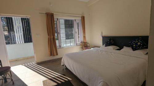 a bedroom with a large bed and two windows at Misty Mount By Himalayan Tree Hotels in Bhowāli