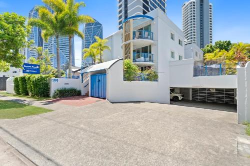 a white house with a blue garage in front of tall buildings at Coastline Escape Renovated Unit - Great Location - Quiet Area - Parking Included in Gold Coast