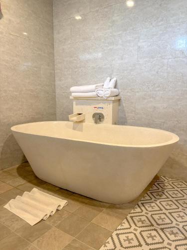 a white bath tub in a bathroom with towels at Adil Villa & Resort in Ubud