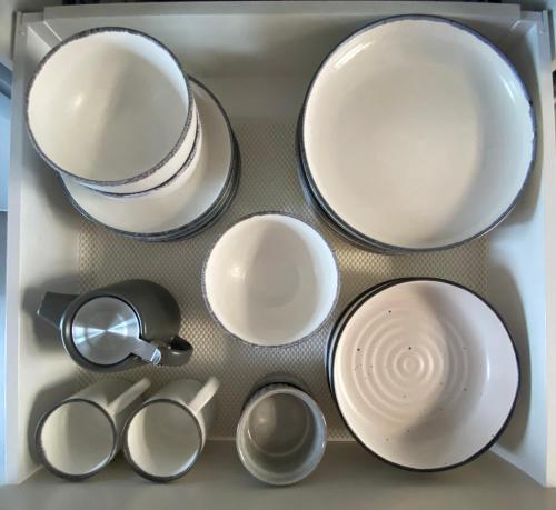 a drawer filled with plates and cups and utensils at Beautiful Bream Bay Studio - Ruakaka in Ruakaka