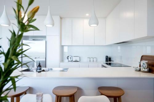 a kitchen with white cabinets and wooden stools at Anglesea Coastal Getaway - Prime Location in Anglesea