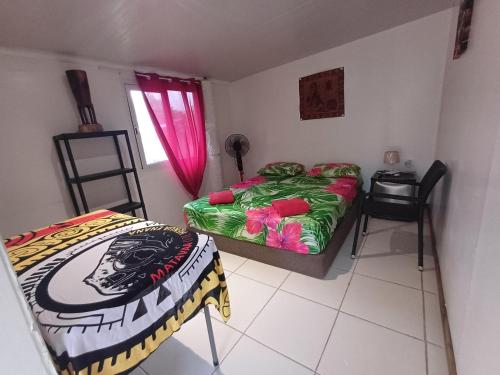 a bedroom with two beds and a table and a window at Pitake Lodge 2 in Nuku Hiva