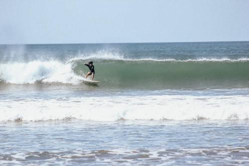 a man riding a wave on a surfboard in the ocean at Nimbu Beachhouse in Transito