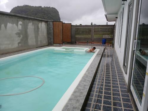 a man laying in a swimming pool on a roof at Buketree homestay satun in Ban Khok