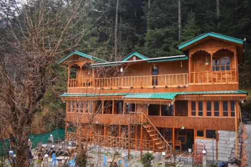 a large wooden house with a staircase in front at Rustic wood house - A village home stay in Jibhi Valley in Jibhi
