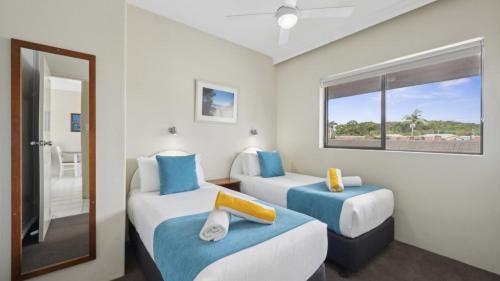 two beds in a room with a window at Ocean Parade 4 - Affordable, Pool, Spa, Cafes, Sleeps 4 in Coffs Harbour