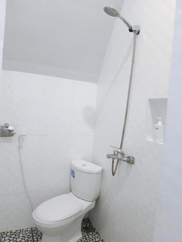 a white bathroom with a toilet and a shower at Noel Cottage in Ngurblut
