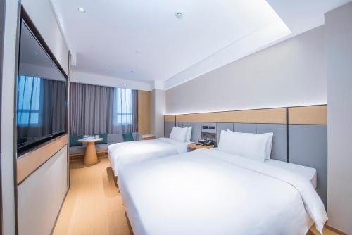 a hotel room with two beds and a flat screen tv at Ji Hotel - Shanghai Nanjing Road People's Square in Shanghai