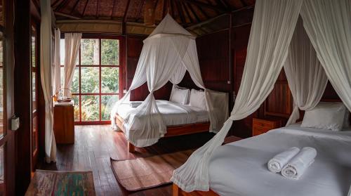 a bedroom with two beds with mosquito nets at Kebun Kita Ecolodge By Bali Cabin in Padangan