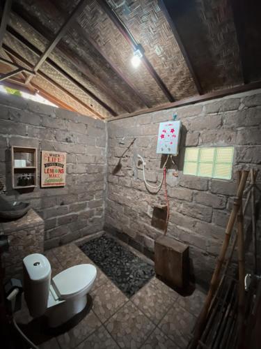 a bathroom with a toilet in a brick wall at Kebun Kita Ecolodge By Bali Cabin in Padangan