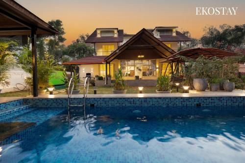 a villa with a swimming pool in front of a house at EKOSTAY - Shelby Villa in Panchgani