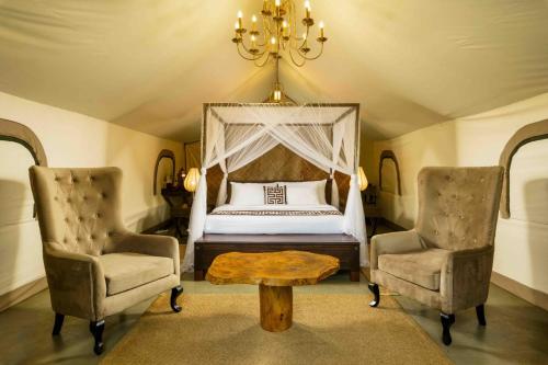 a bedroom with a bed and two chairs and a table at Makini Bush Camp, Yala in Yala