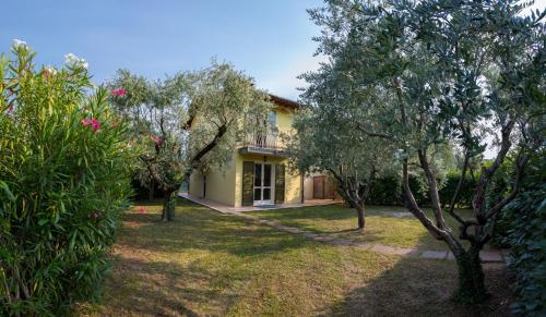 a yellow house with trees in the yard at Wonderful villa on the Garda Lake with private garden in Salò