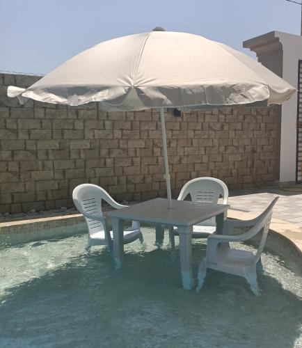 a table and chairs under an umbrella next to a pool at Relaxing Villa with pool in El Haouaria