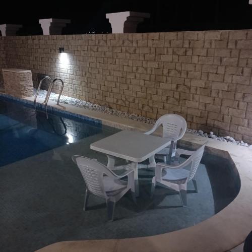 a table and chairs next to a swimming pool at night at Relaxing Villa with pool in El Haouaria