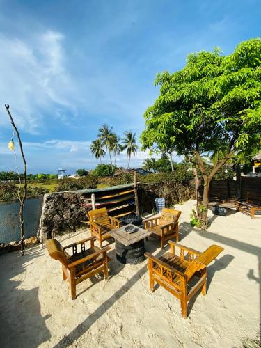 a group of benches and a picnic table on the beach at Novena Bungalow in Pulau Helihana