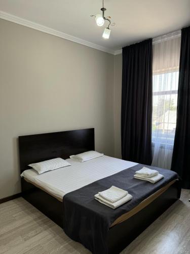 a bedroom with a large bed with two towels on it at Apart Hotel in Shymkent