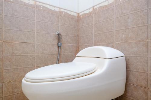 a white toilet in a bathroom with tiled walls at RedDoorz at Savitri Hotel in Yogyakarta