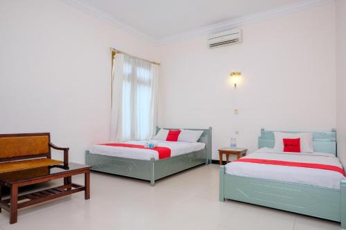 a bedroom with two beds and a chair and a window at RedDoorz at Savitri Hotel in Yogyakarta