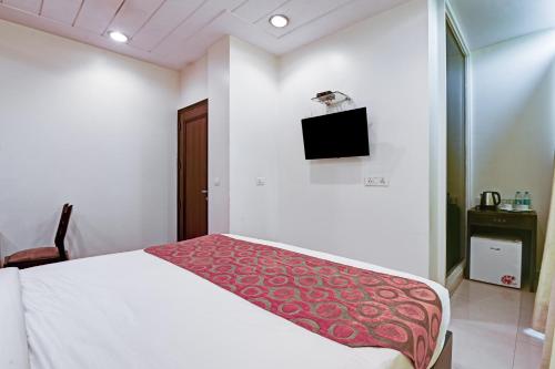 a bedroom with a bed and a tv on the wall at New Ammby Inn - Lajpat Nagar in New Delhi