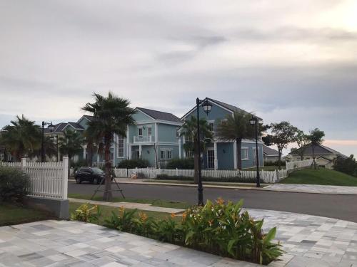 a row of houses with a white fence and palm trees at Novaworld Phan Thiet in Bình Sum