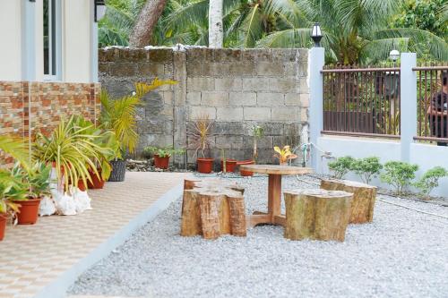 a patio with a table and logs and plants at AJ Residences Apartelle Camotes RedPartner in Esperanza