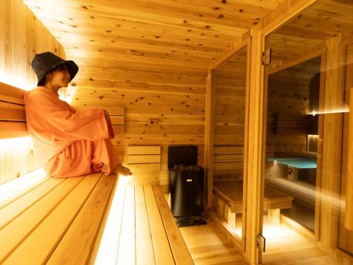 a woman is sitting in a sauna at saunea白州 in Hokuto